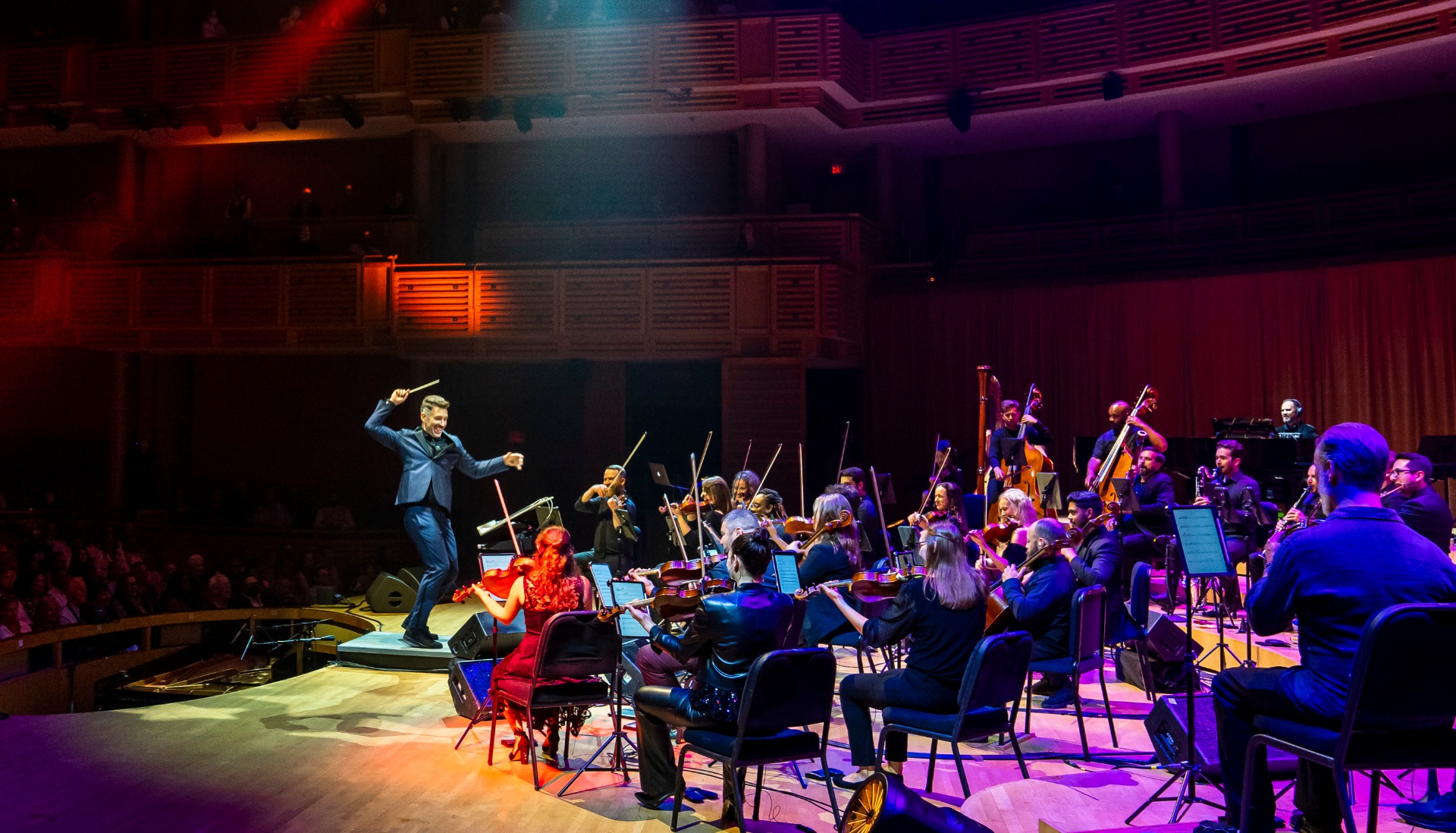 Nu Deco Ensemble live on stage with conductor Jacomo Bairos and full orchestra under dramatic concert lighting